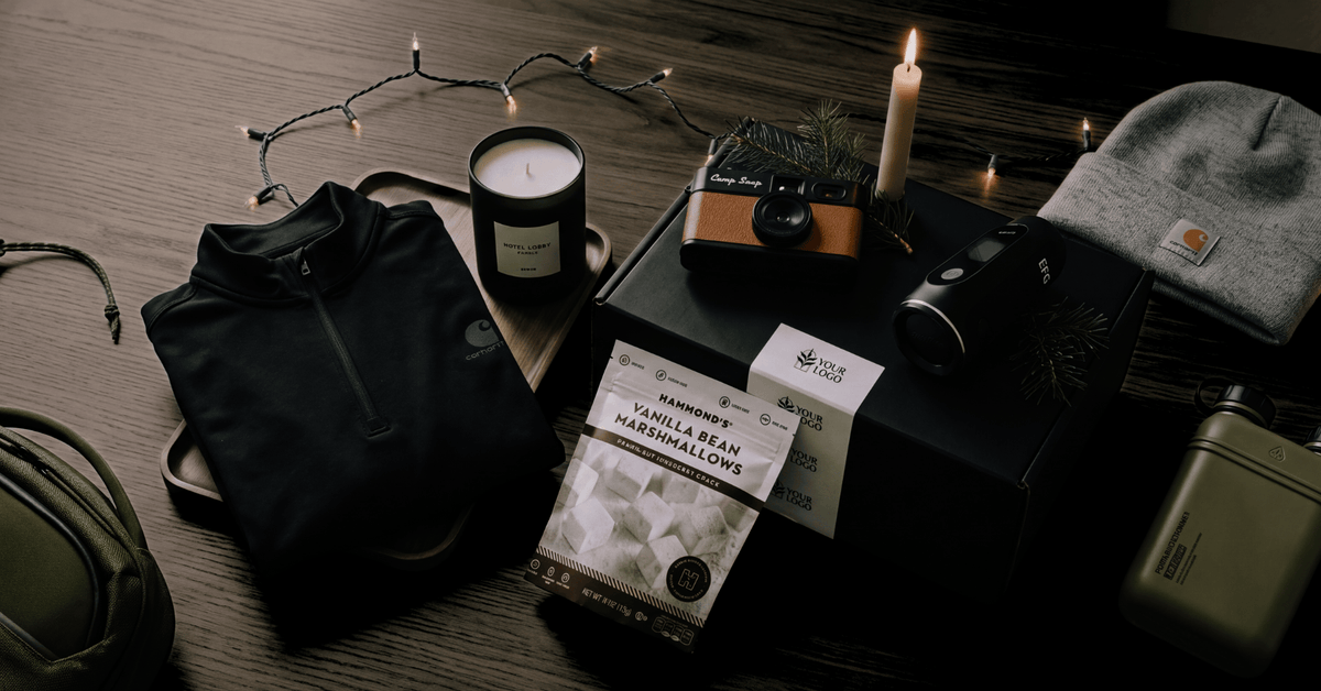 flatlay with premium gits: custom gift box, carhartt beanie, camp snap camera, candle, jacket, and power bank